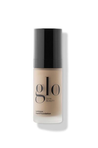 A bottle of glo foundation is sitting on a white surface.