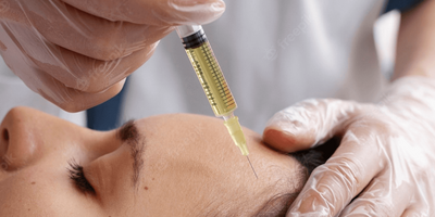 A woman is getting a botox injection in her forehead.