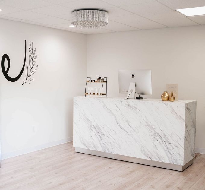 A white marble counter with a computer on it in a room.