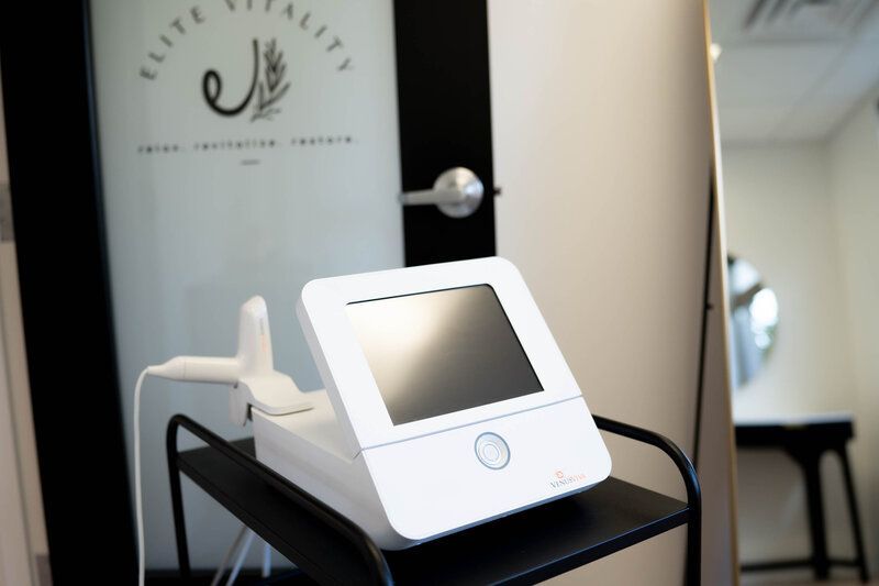 A white device is sitting on a shelf in front of a door that says elite vitality