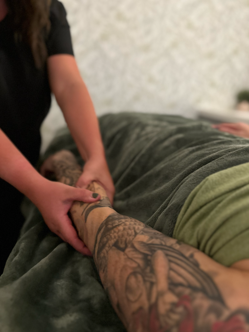 A woman is giving a tattooed man a massage