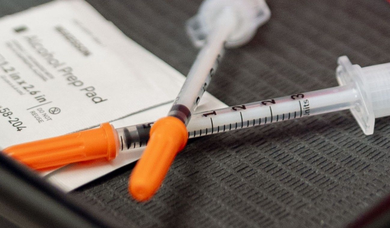 A woman is holding a syringe and a bottle in her hands.