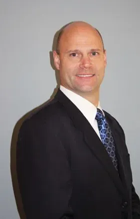 A man in a suit and tie is smiling for the camera.