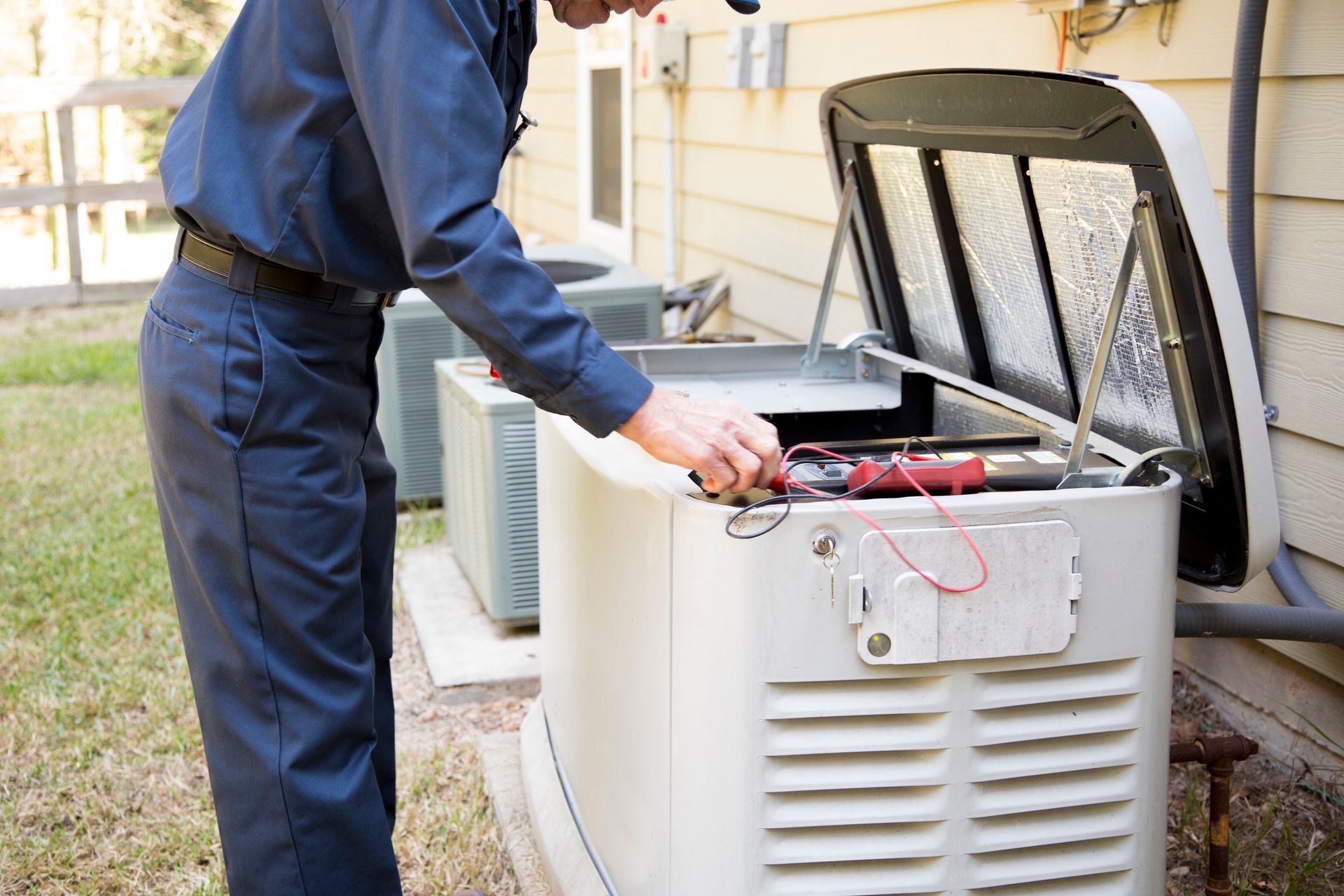 A man is working on a generator outside of a house.