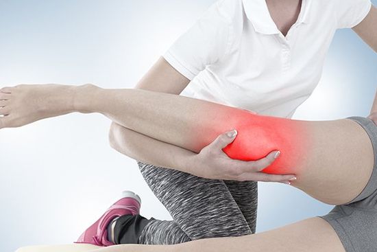 una fisioterapista che sorregge una gamba di una donna con il ginocchio infiammato