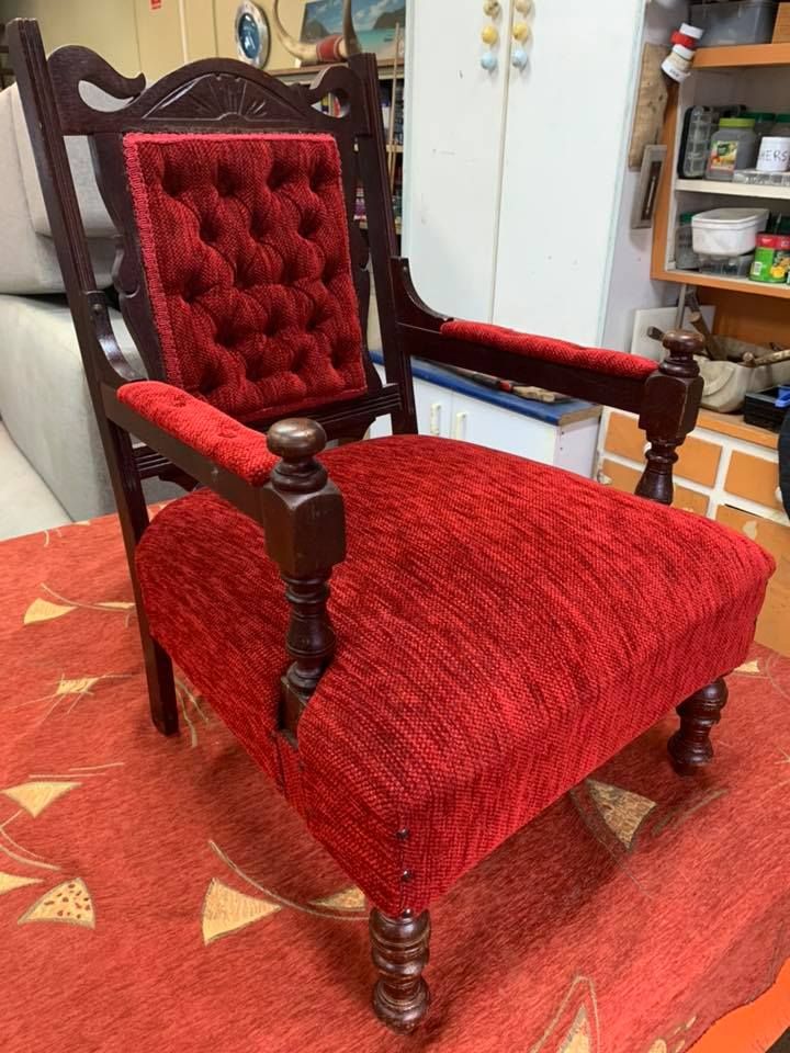 A Red Chair is Sitting on a Red Rug in a Room — Aztak Upholstery In Manunda, QLD