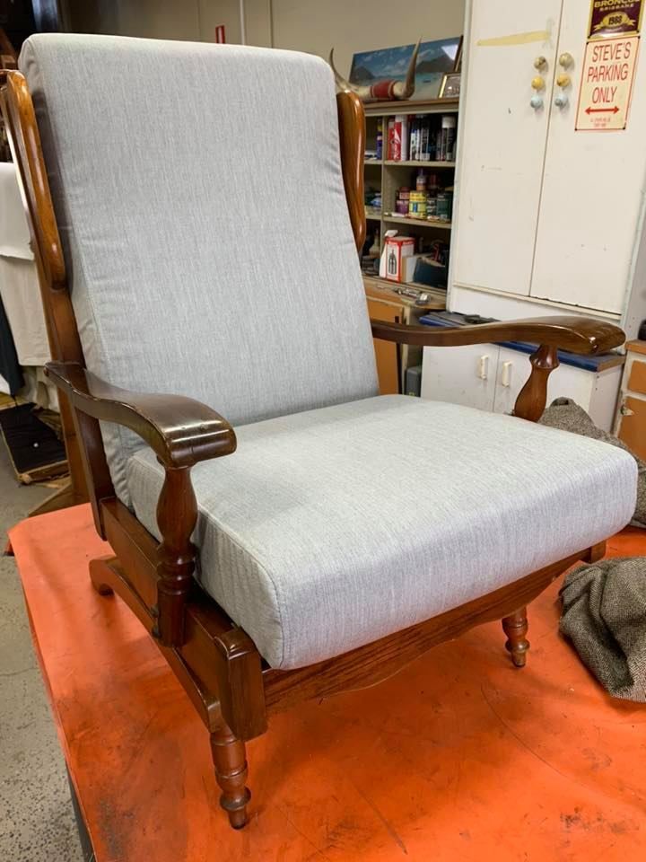 A Wooden Rocking Chair With a Grey Cushion is Sitting on Top of an Orange Table — Aztak Upholstery In Manunda, QLD