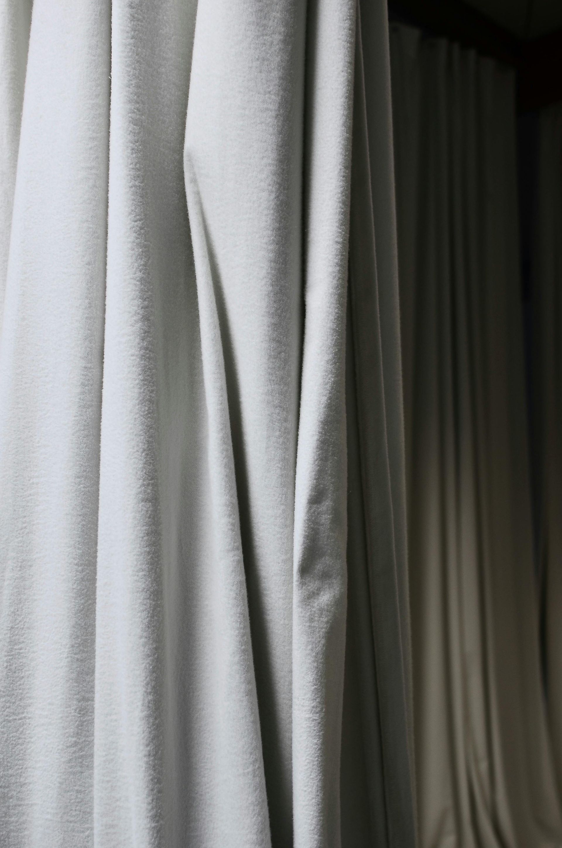 A close up of a white curtain hanging on a window.
