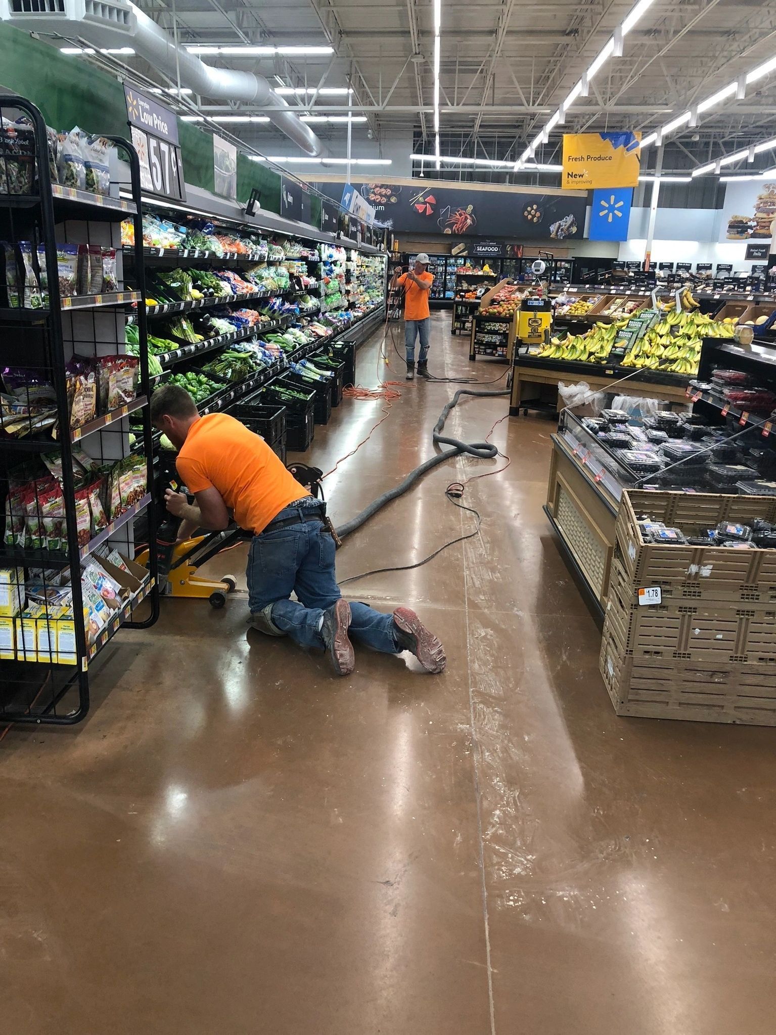 A man is cleaning the floor of a grocery store with a vacuum cleaner.