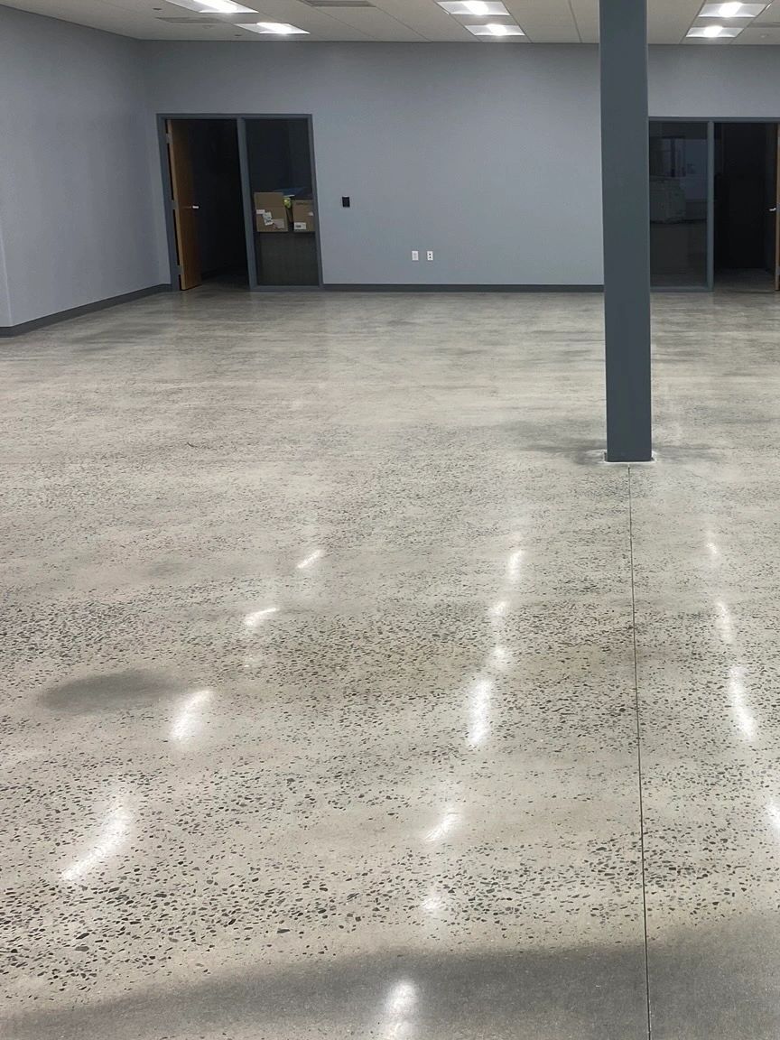 A large empty room with a concrete floor and a pillar.