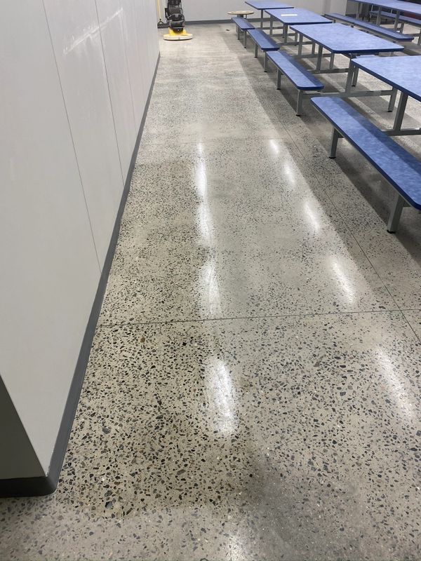 A long hallway with blue benches and tables in a school cafeteria.