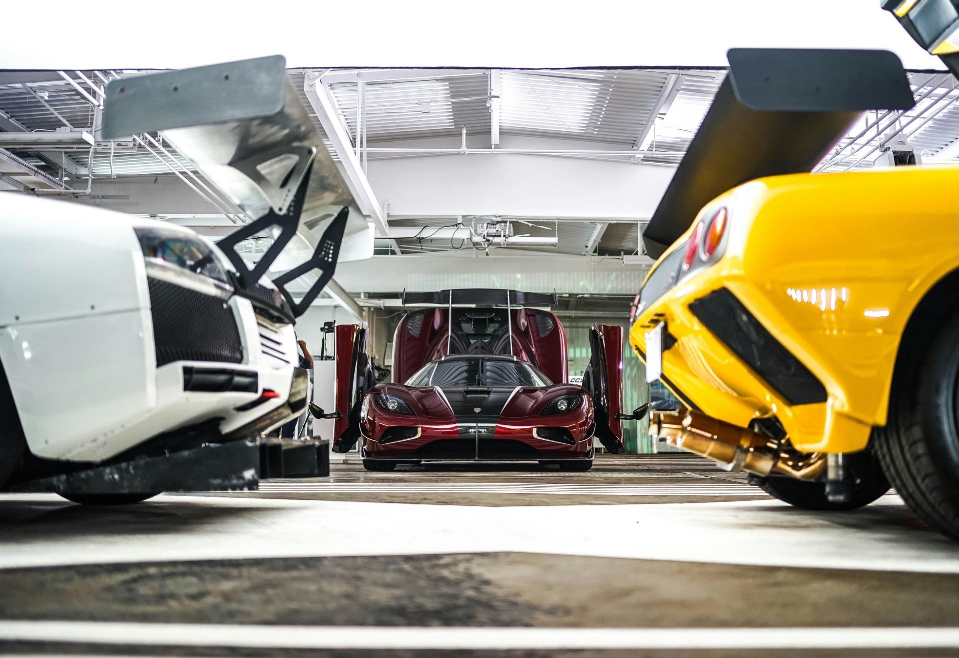 Three sports cars with large wings parked inside.
