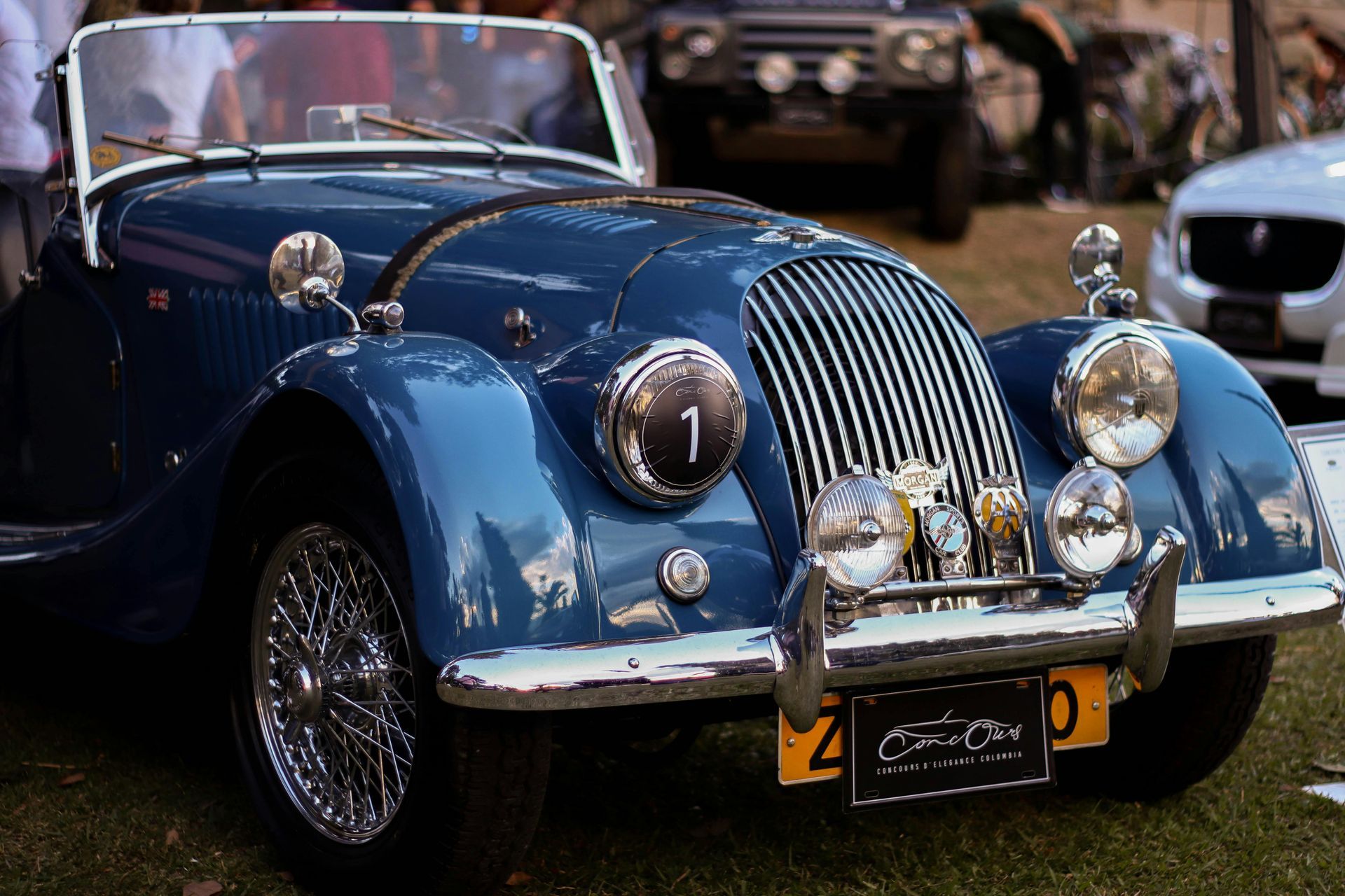 Blue vintage Morgan sports car with chrome details at an outdoor car show.