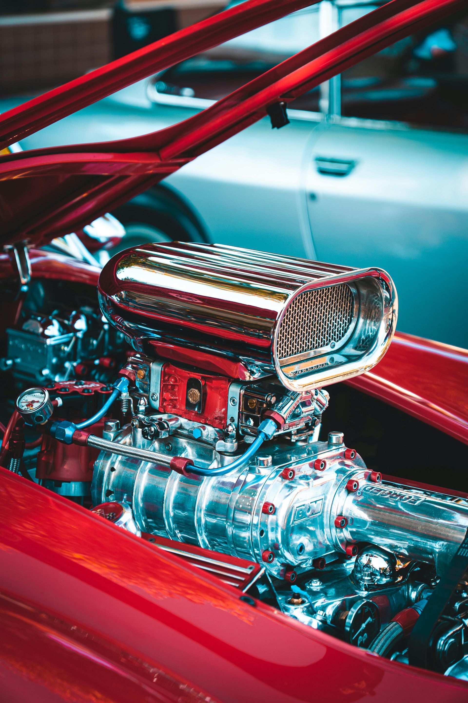 Chrome car engine with large air intake, red frame.