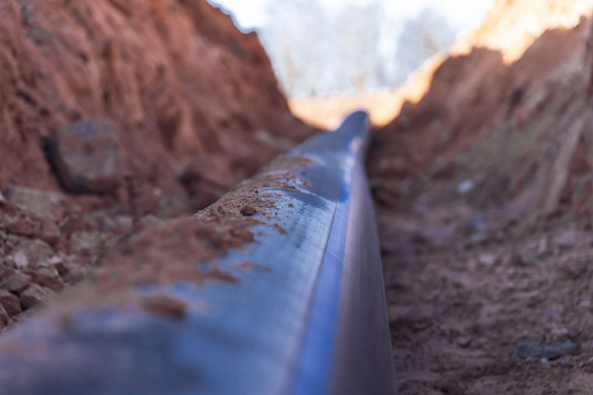 Close-up of a black pipe running through a narrow rocky trench
