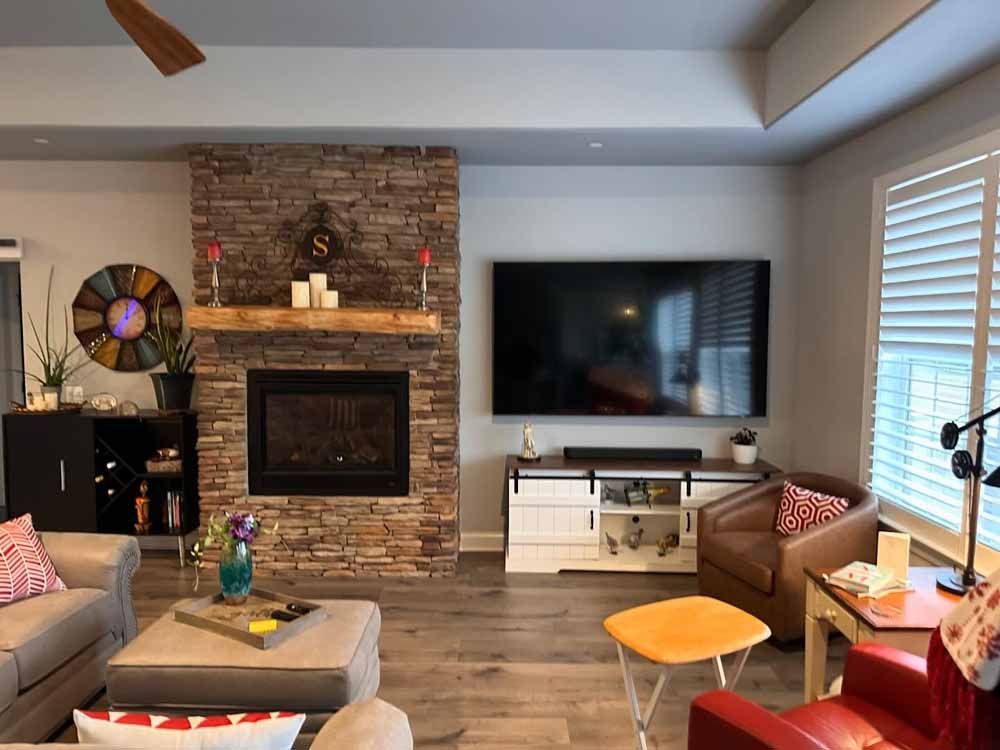 Living room with stone fireplace, TV, and modern furniture.