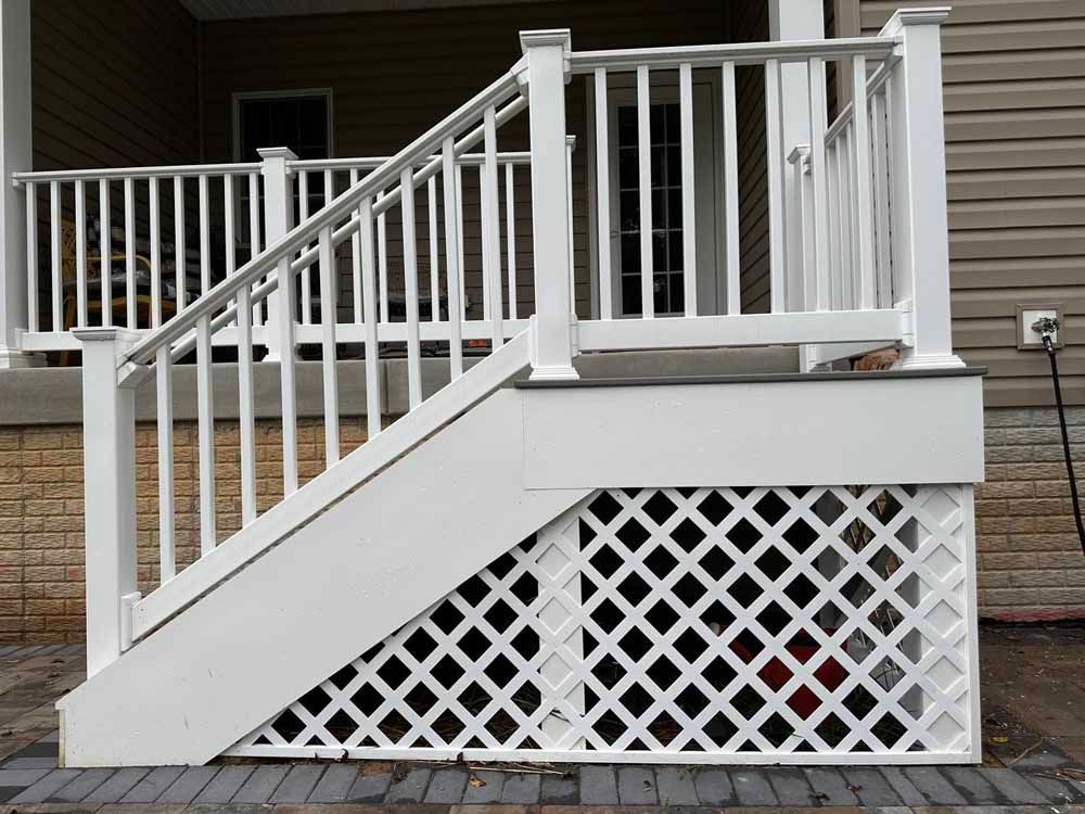 White painted wooden porch stairs with lattice under the landing and railings.