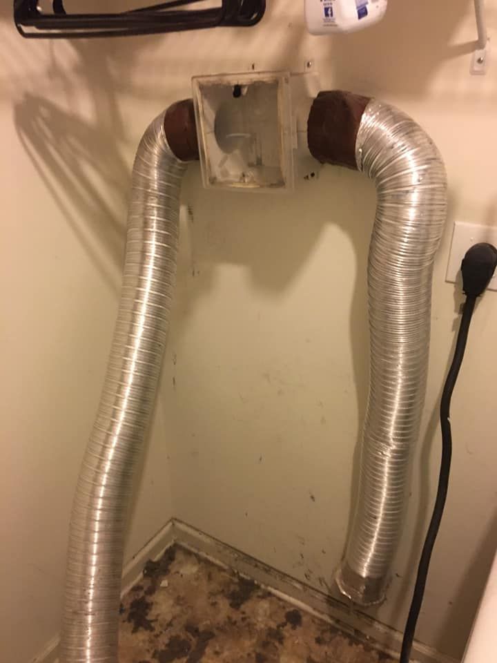 Two aluminum ducts are attached to a wall in a bathroom.
