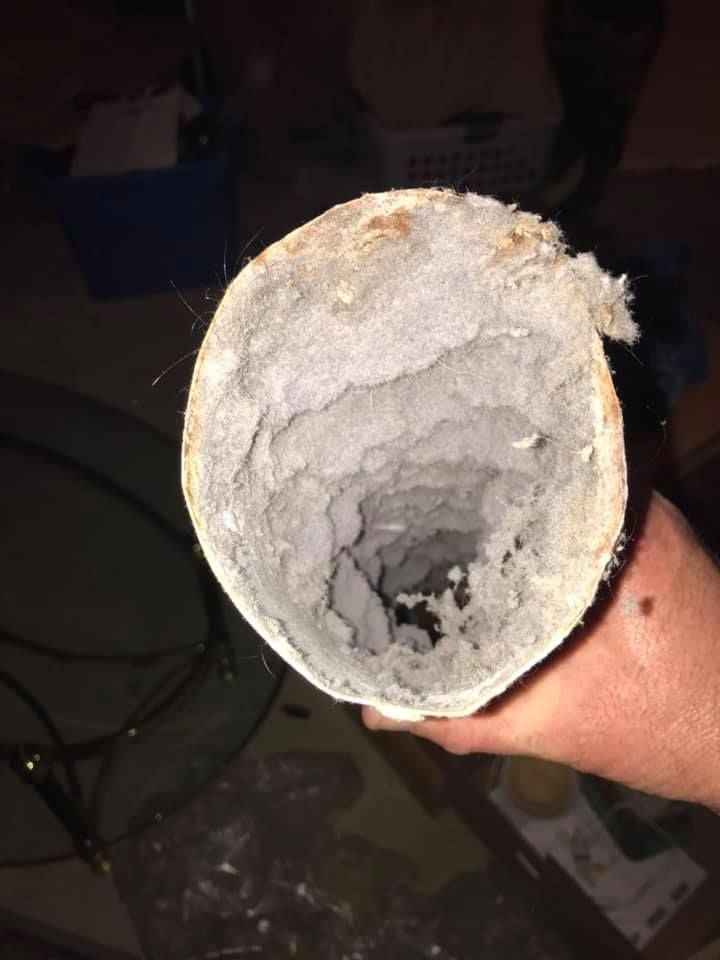 A person is holding a dirty pipe in their hand