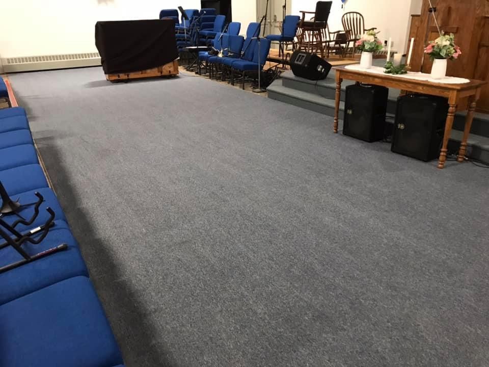 An empty church with blue chairs and speakers on the floor.
