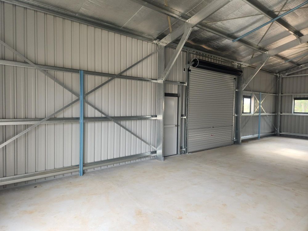 An Empty Warehouse With A Roller Door And A Window — Whit Coast Sheds in Moranbah, QLD