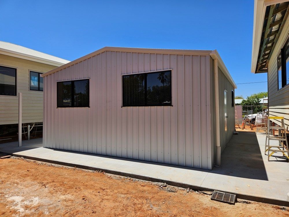 A Small Building With A Lot Of Windows Is Being Built — Whit Coast Sheds in Moranbah, QLD