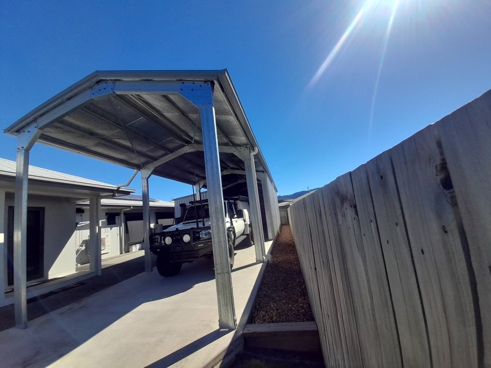 A Car Is Parked Under A Carport Next To A Wooden Fence — Whit Coast Sheds in  Gregory River, QLD