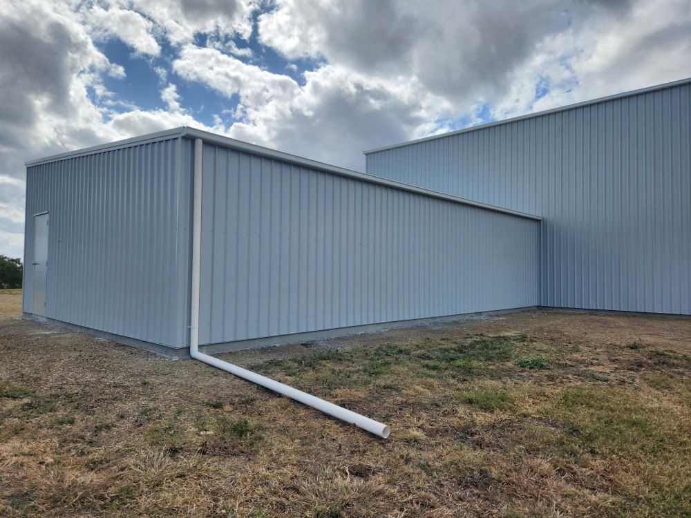 A Large White Building With A White Gutter On The Side Of It — Whit Coast Sheds in Gregory River, QLD