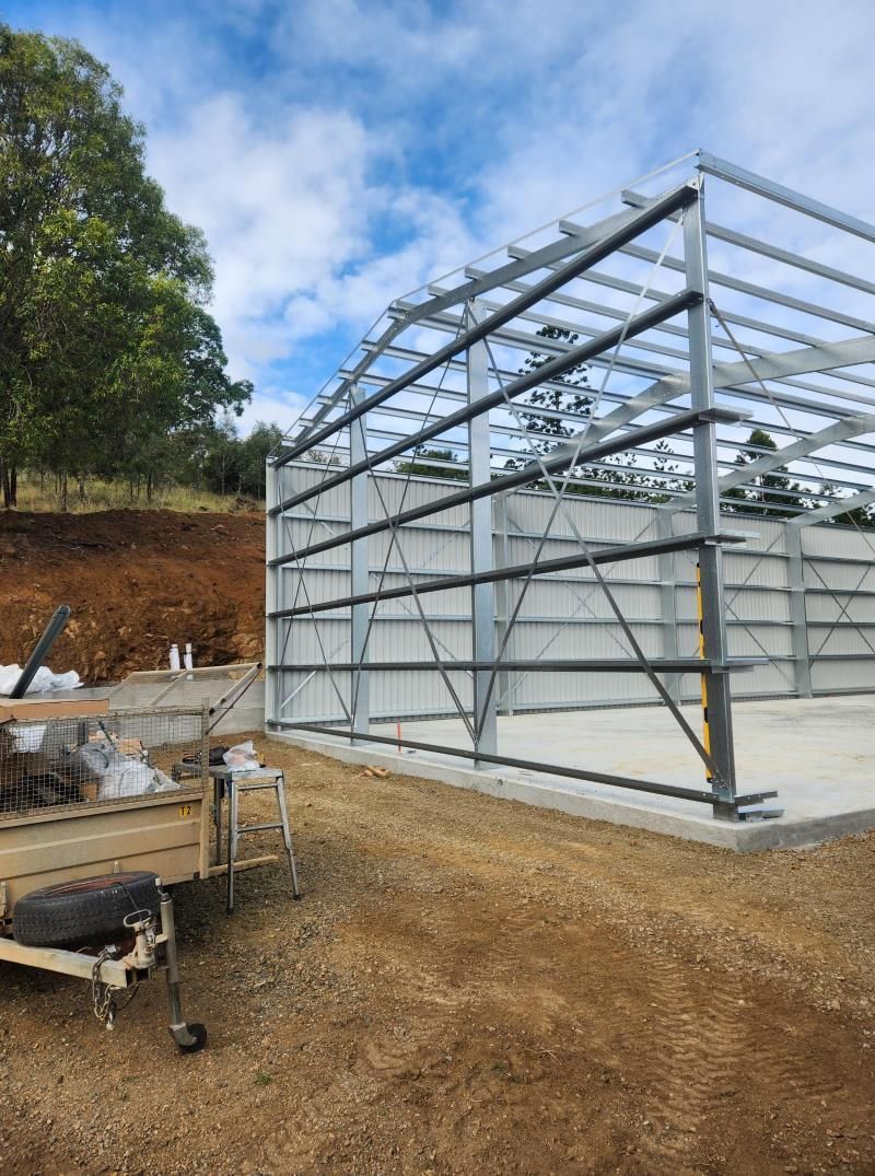 A Large Metal Structure Is Being Built In The Middle Of A Dirt Field — Whit Coast Sheds in Gregory River, QLD