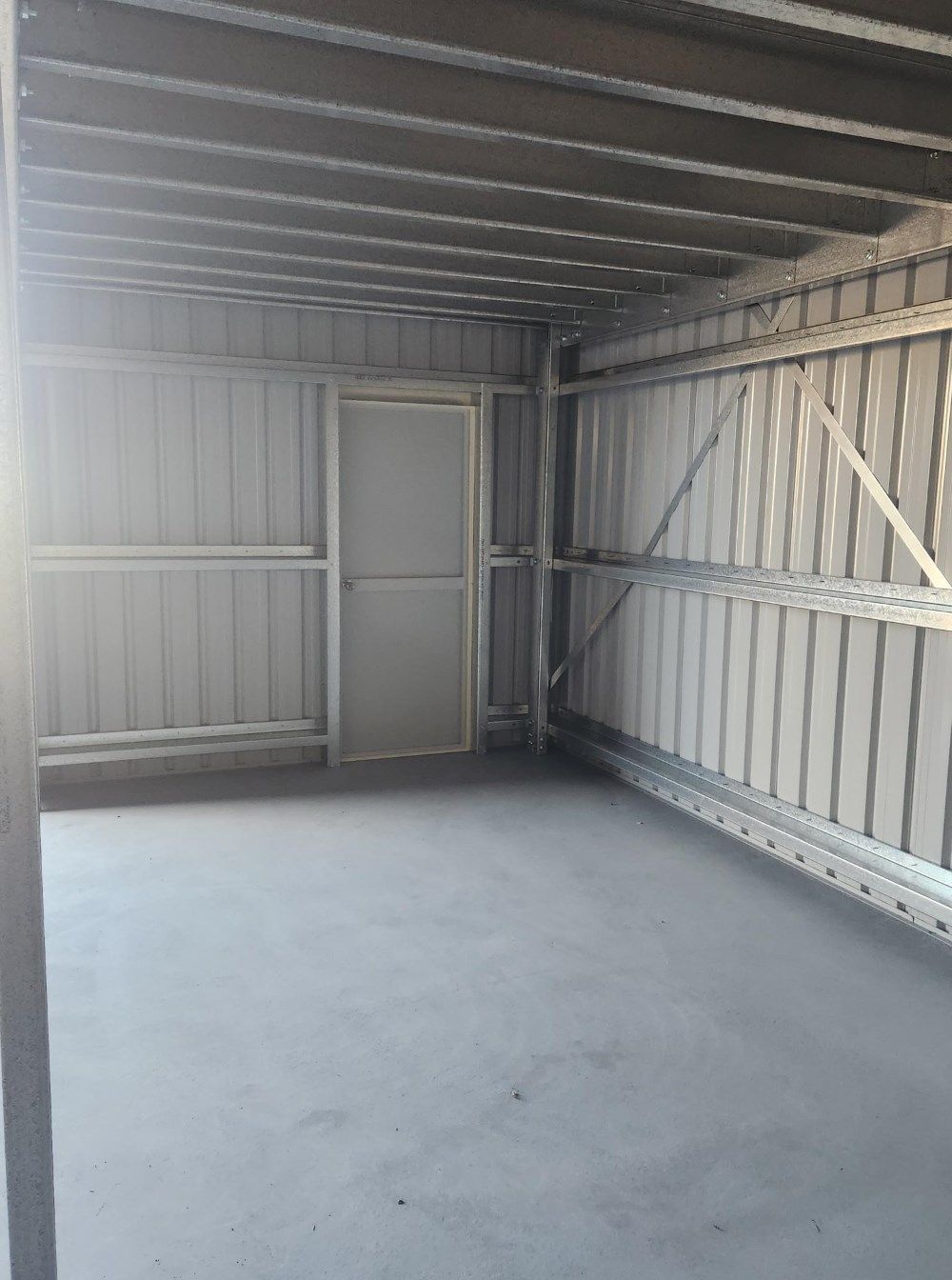 An Empty Garage With A Door And A Ceiling — Whit Coast Sheds in Gregory River, QLD