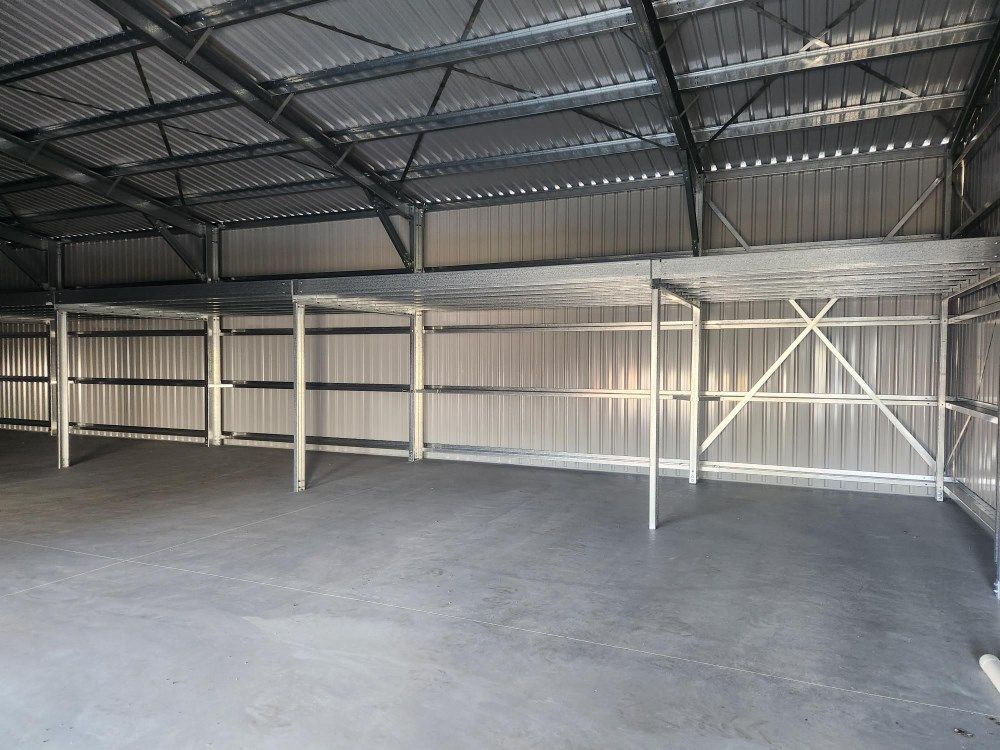 An Empty Warehouse With A Metal Roof And A Concrete Floor — Whit Coast Sheds in Bowen, QLD