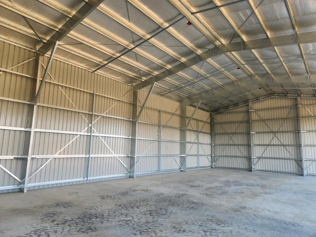 A Large Empty Warehouse With A Metal Roof — Whit Coast Sheds in Bowen, QLD