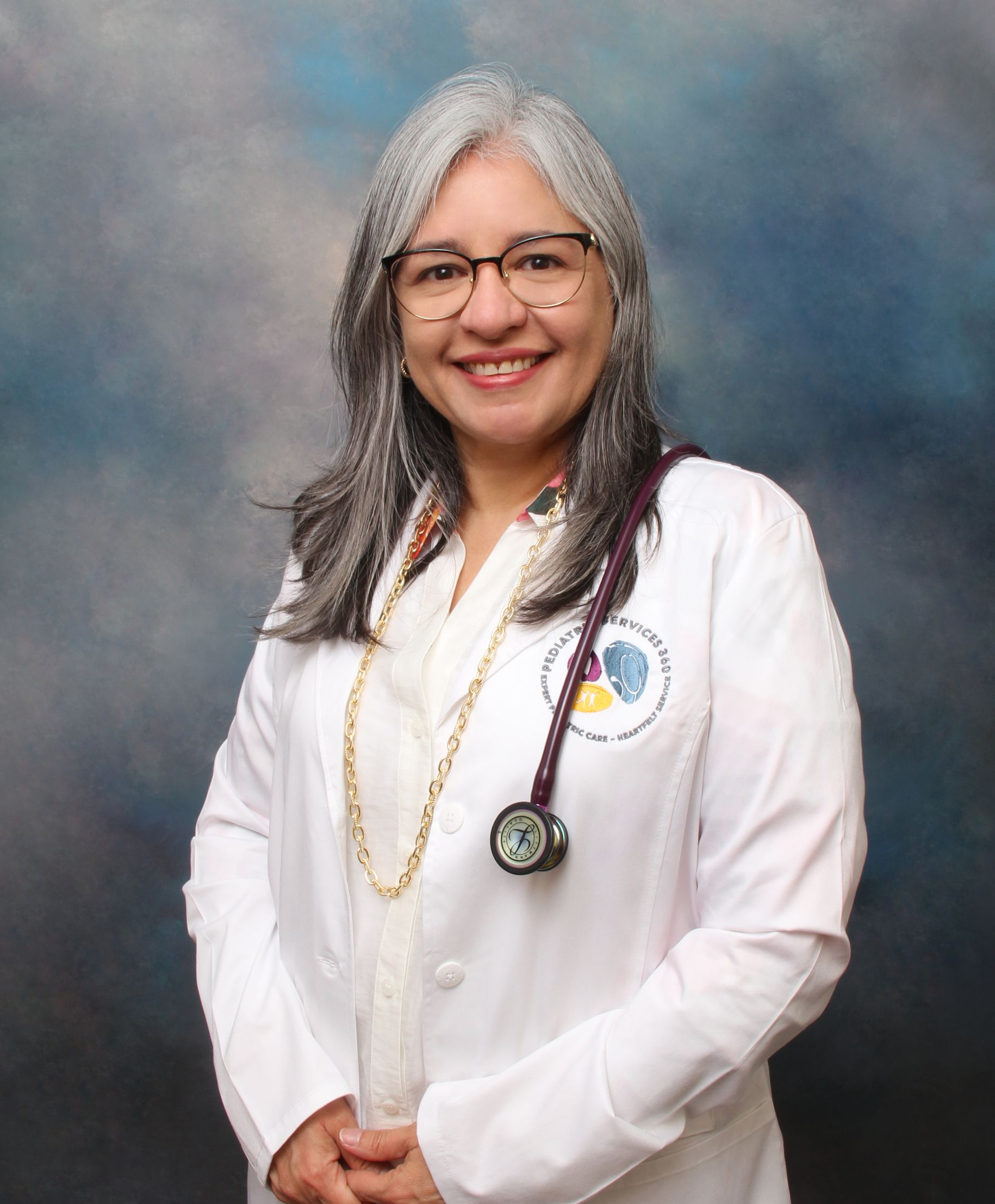 Woman in white coat with stethoscope, smiling, looking at the camera.