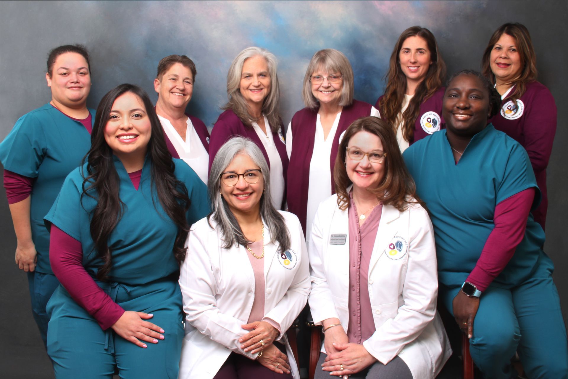 Staff members in teal and burgundy, posing in front of a blue background.