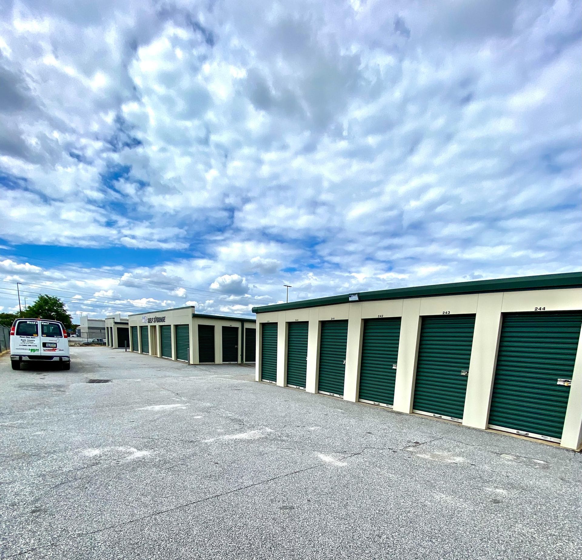 A white truck is parked in front of a row of green garage doors.