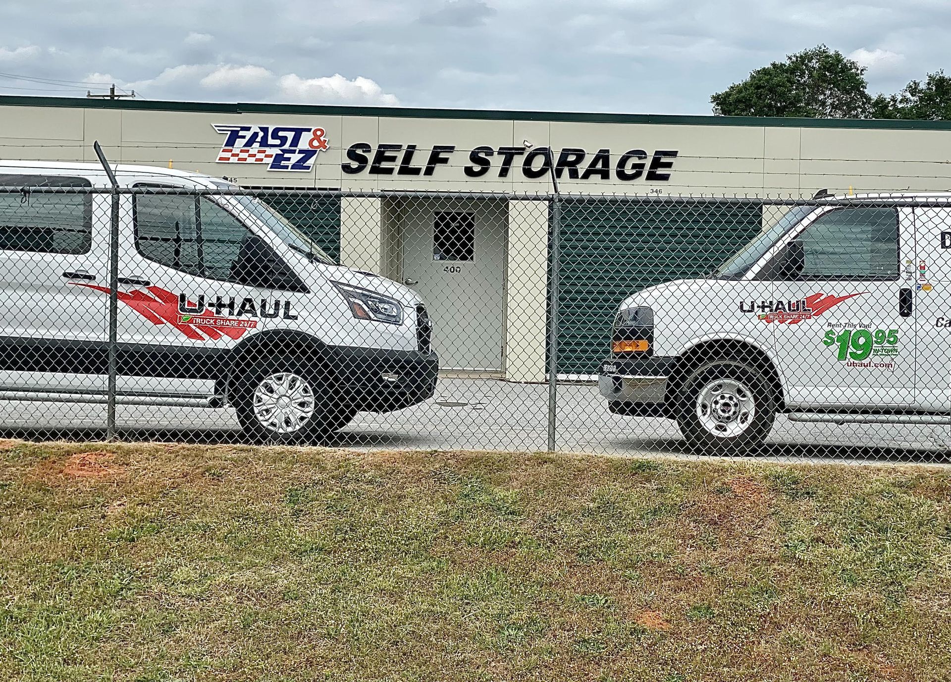 Two vans are parked in front of a self storage building.