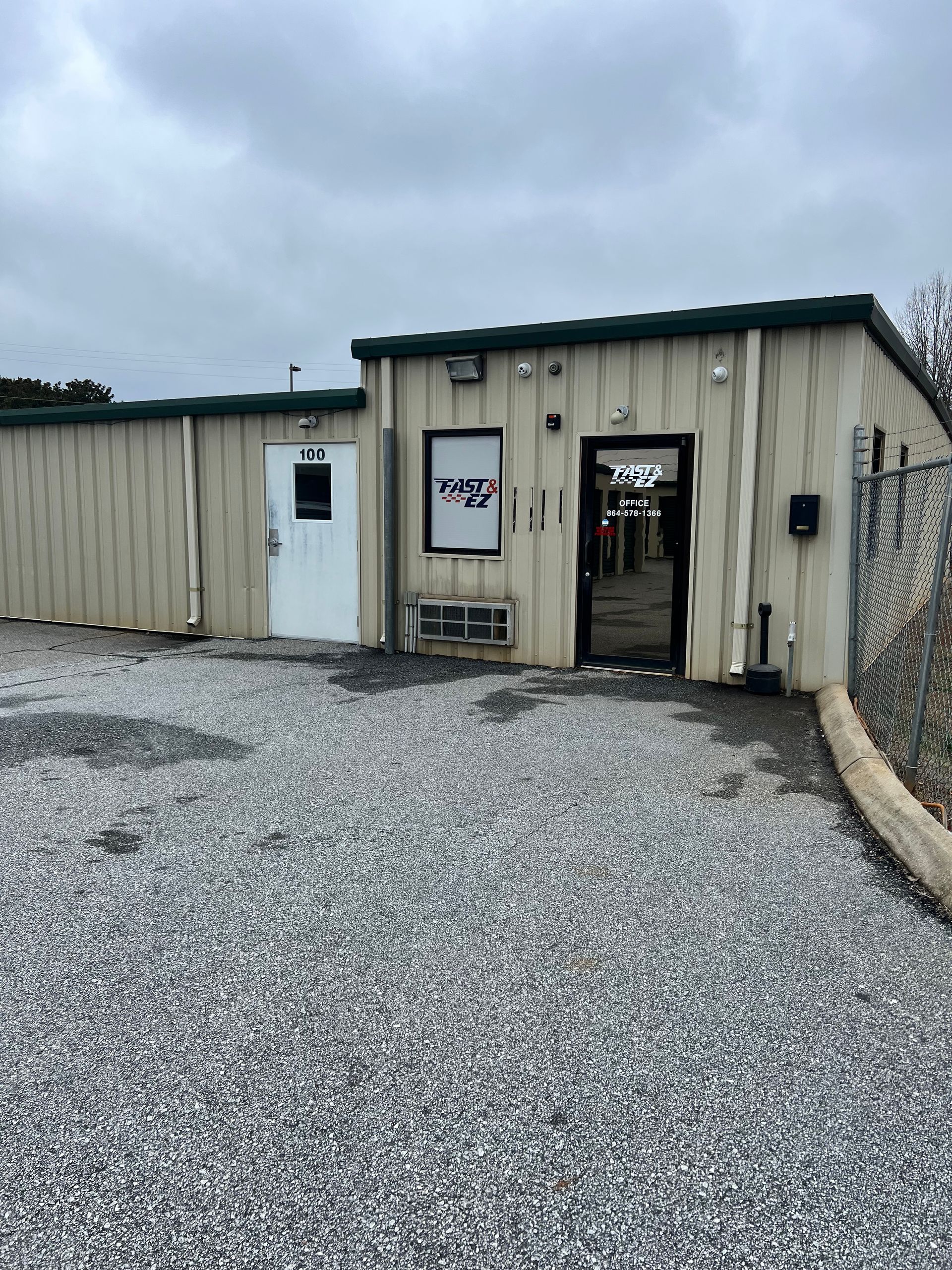 A small building with a gravel driveway in front of it.