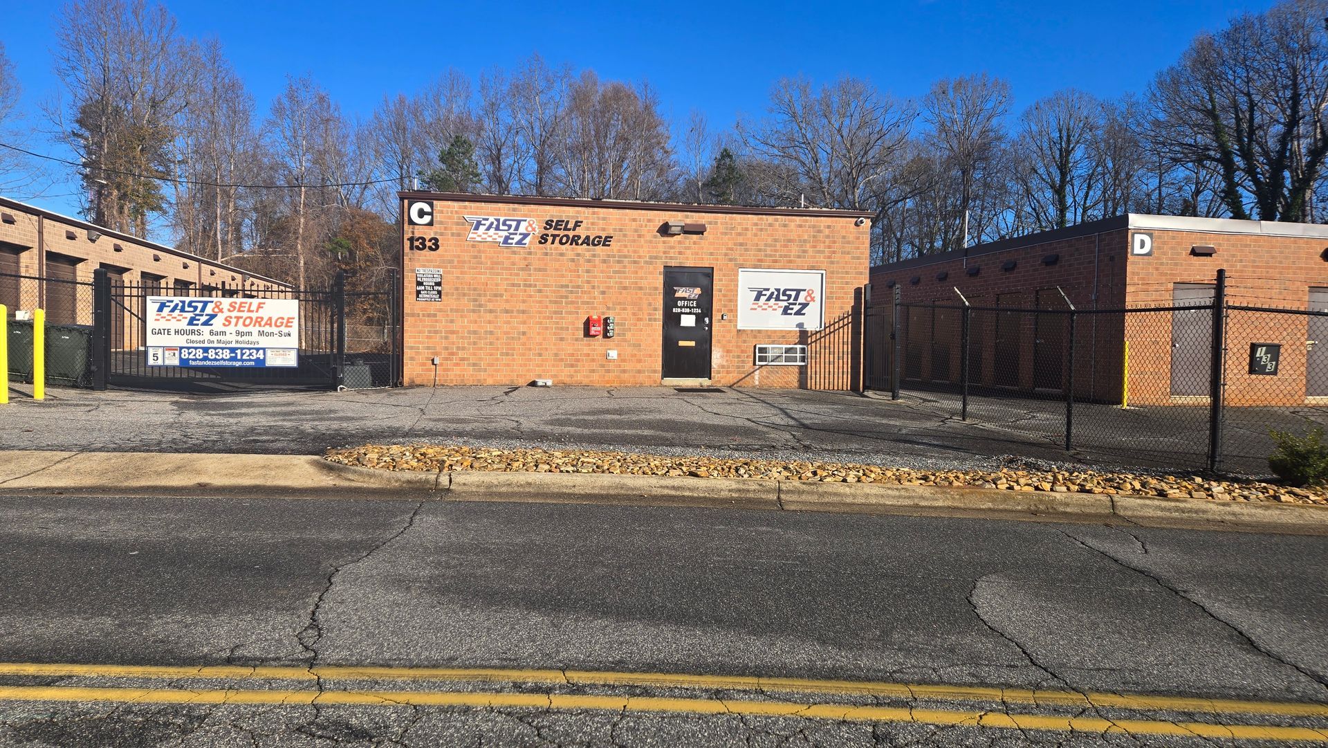 A brick building is sitting on the side of the road next to a fence.