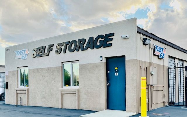 A self storage building with a blue door and a yellow pole in front of it.