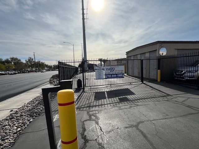 A yellow pole is in front of a fence with a sign on it