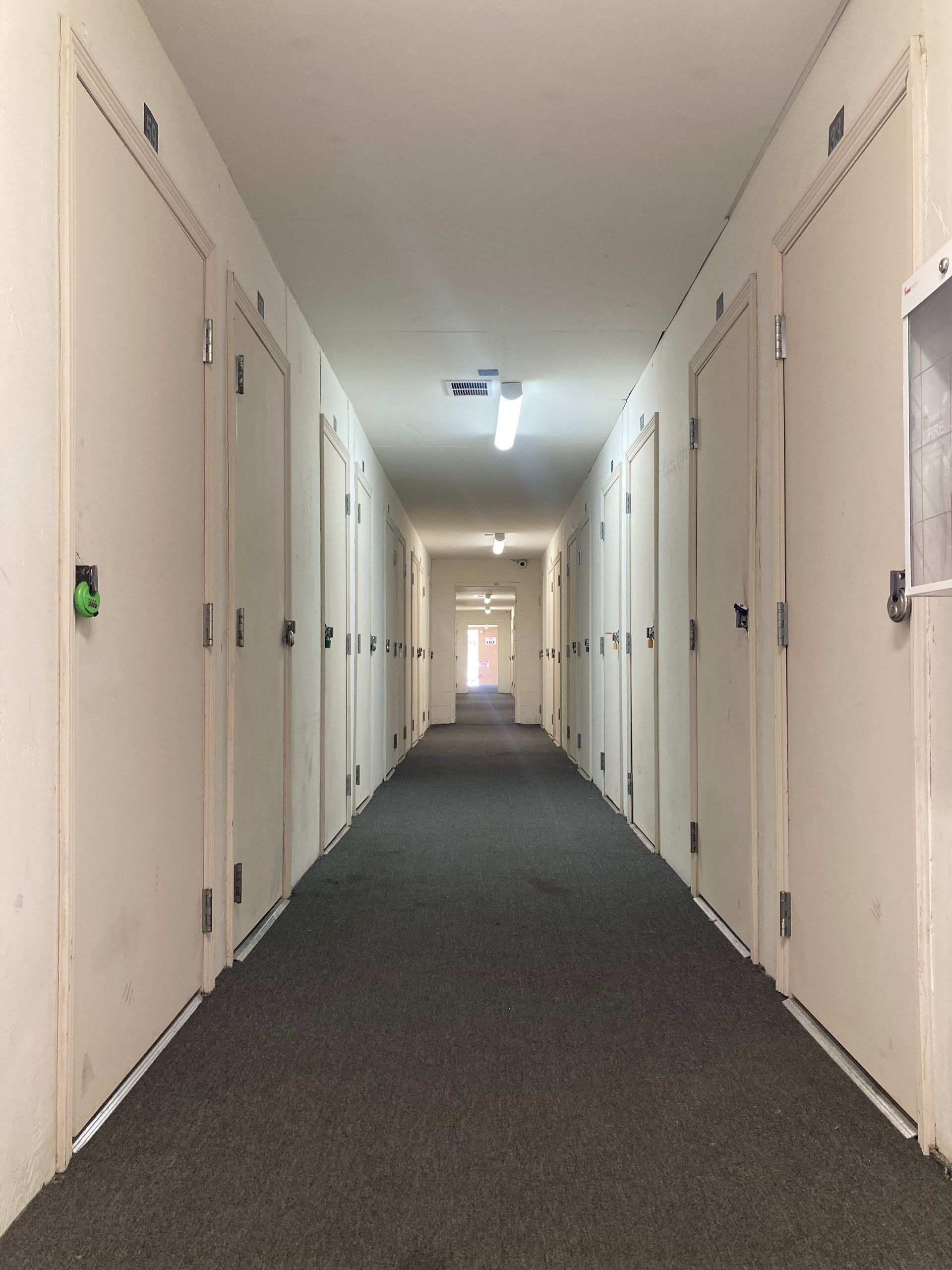 A long hallway with white doors and a gray carpet
