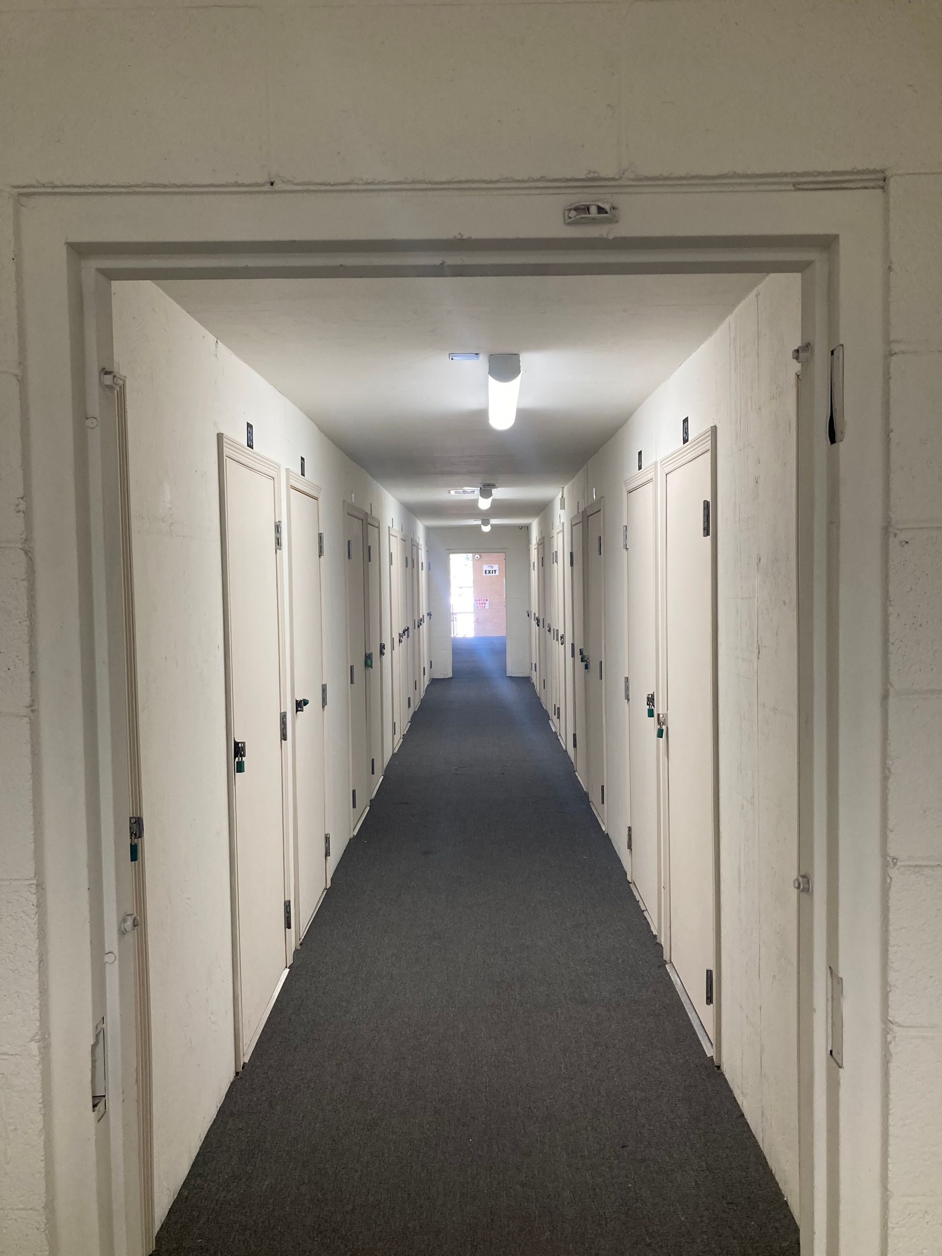 A long hallway with white walls and gray carpet