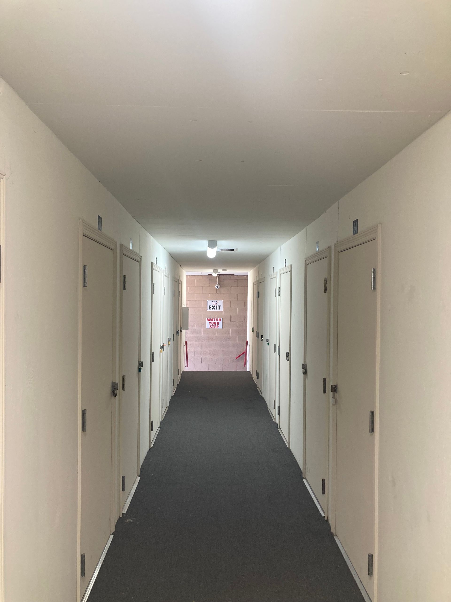 A long hallway with white walls and black carpet