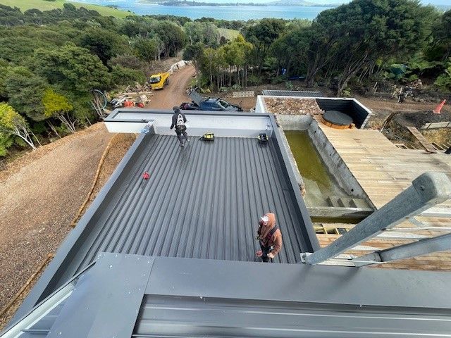 A Man is Standing on the Roof of a Building — Auckland, NZ — Pro Roofing