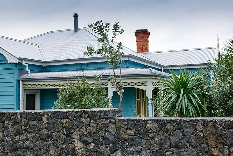A Blue House with a Stone Wall in Front of it — Auckland, NZ — Pro Roofing
