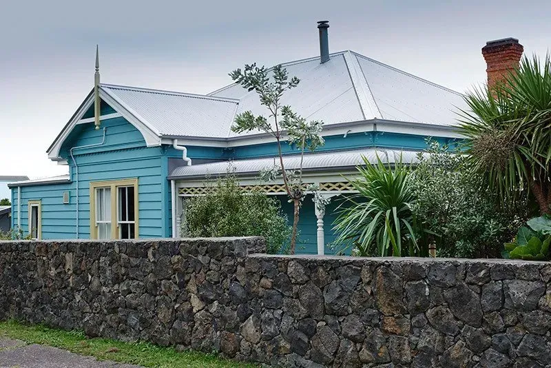 A Blue House with a Stone Wall — Auckland, NZ — Pro Roofing