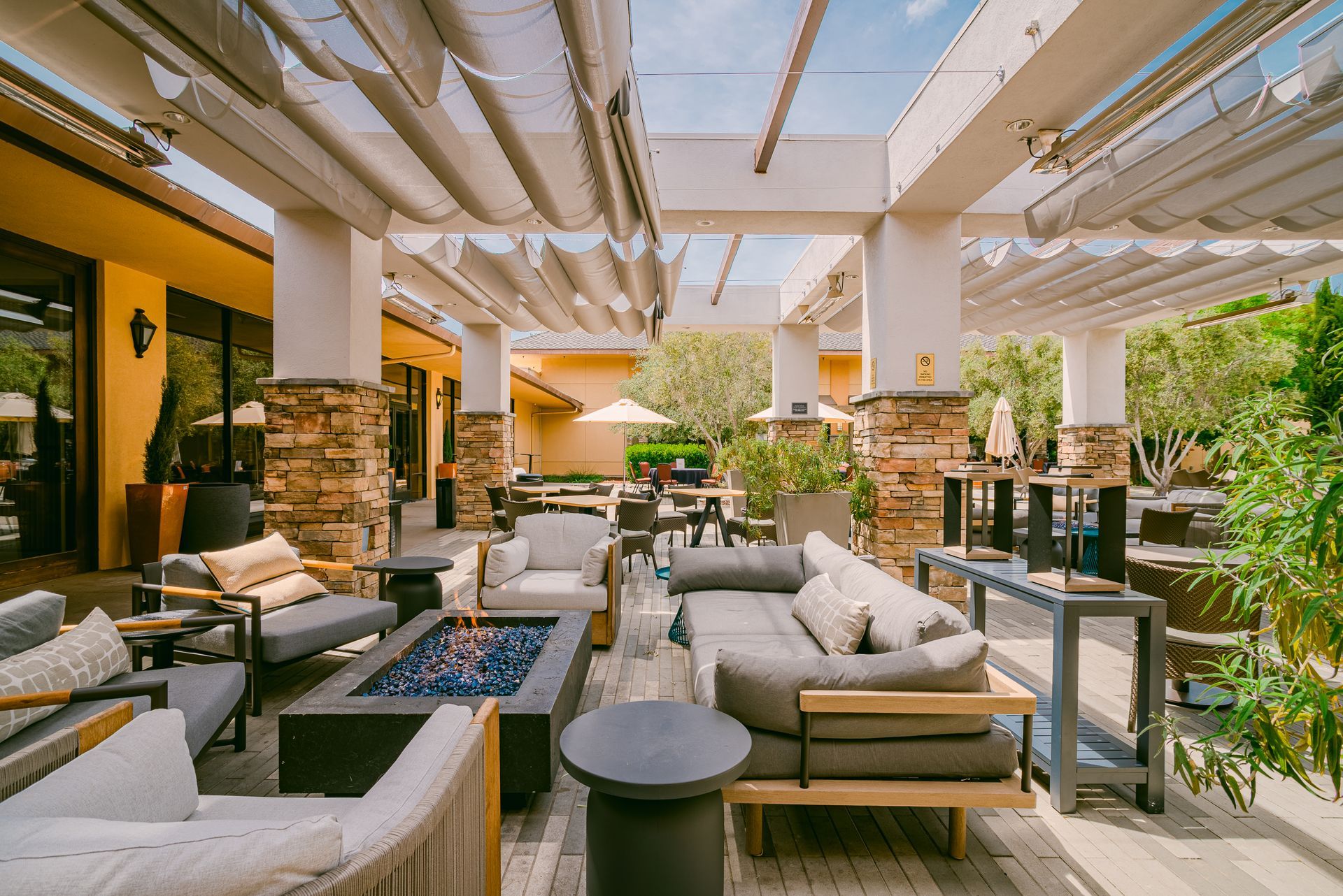 Outdoor patio with seating, fire pit, and overhead shade structure.