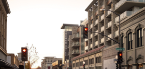 City street with buildings, traffic lights, and overcast sky.