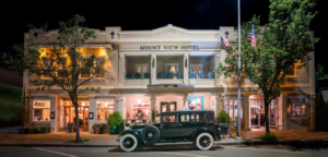 Nighttime view of the Mount View Hotel with a vintage car parked out front.