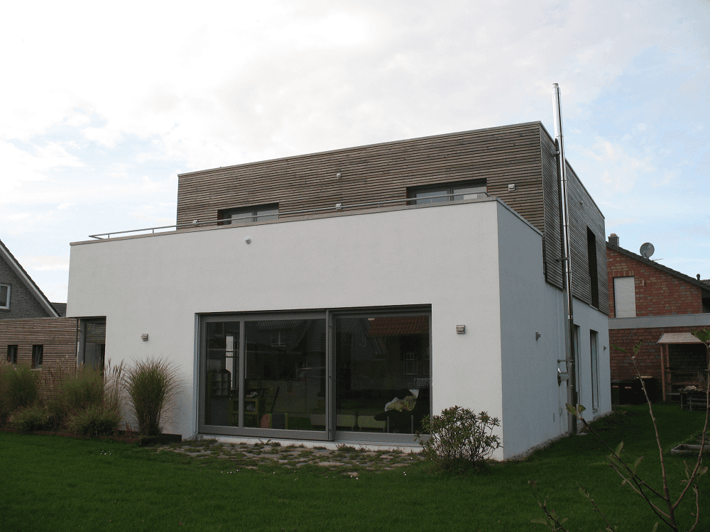 Modernes weißes Haus mit Flachdach und großen Glasschiebetüren, Kamin.